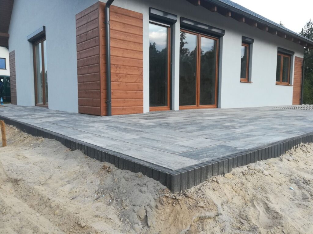 Gniewino - Nowoczesne układanie kostki brukowej wokół nowo wybudowanego domu, z widoczną estetyczną nawierzchnią i granicą z kostki brukowej.